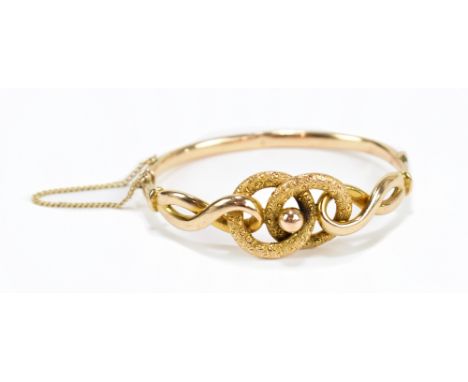 A yellow metal snap bangle with safety chain, approx 11.2g.