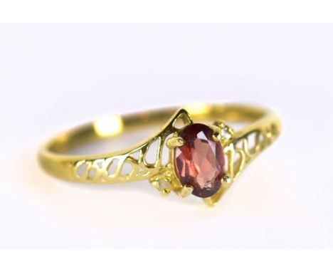 A yellow metal dress ring set with red coloured oval cut stone and white stone chips, stamped 375 to band interior, size N, a