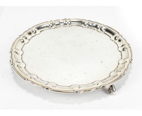 WILLIAM HUTTON &amp; SONS; a George V hallmarked silver card tray with scalloped edge, raised on three scrolling feet, Sheffi