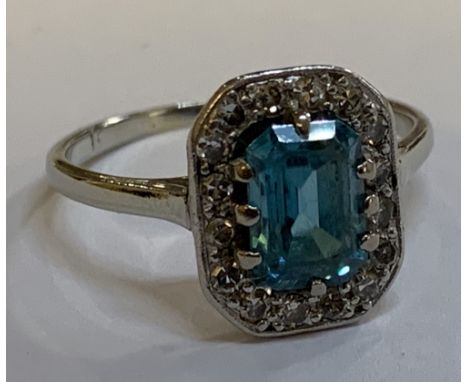 An Art Deco white metal diamond set cocktail ring with central emerald cut stone within a border of diamonds, size O, approx 