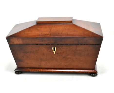 A Victorian mahogany tea caddy of sarcophagus form, with three division interior retaining both lids but no jar, on compresse