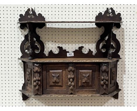 An oak carved wall cupboard with display shelf. 23" wide.