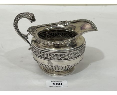 A 19th Century silver helmet form milk jug, the gadrooned body with a border of scrolled foliage and leopard cast handle. 6¼"