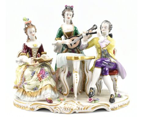 A 20th century gilt porcelain rococo figural scene of two ladies &amp; a man playing music. The scene depicting seated lady s