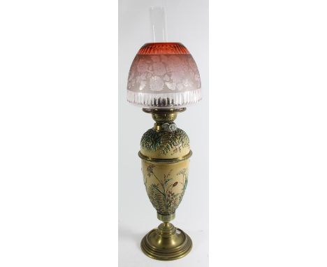 An Aesthetic Movement pottery and brass oil lamp, the body and pull off reservoir with raised fern and foliage decoration, br
