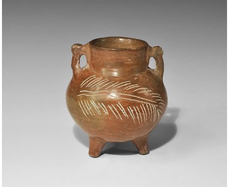1st millennium AD. A burnished ceramic vessel, bulbous with three stub legs, two loop handles to the broad neck, incised fron