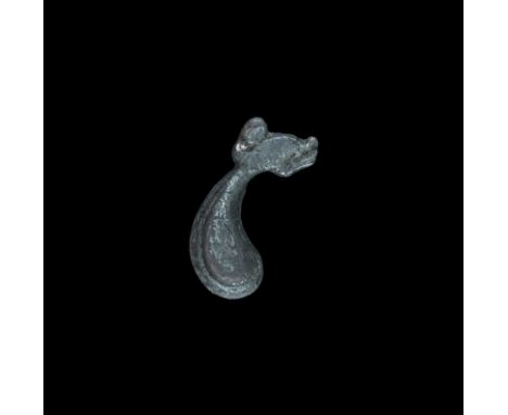 12th century AD. A silver Romanesque style profile beast-head on a comma-shaped plaque with spike to the reverse. 6.50 grams,