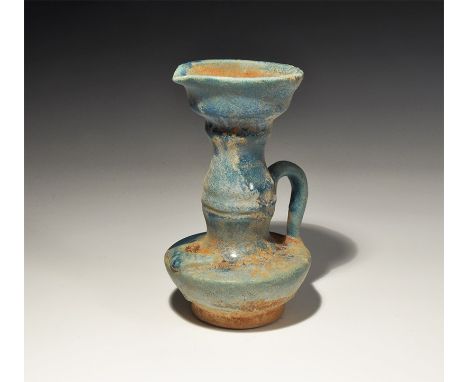 An undated archaistic blue-glazed ceramic jug with tall balustered neck, strap handle, leaf-shaped bowl; applied fish motif t