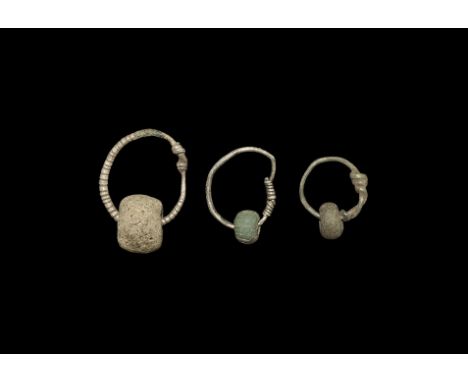 9th-12th century AD. A mixed group of bead pendants comprising: two silver wire hoops each with a green glass annular bead; a