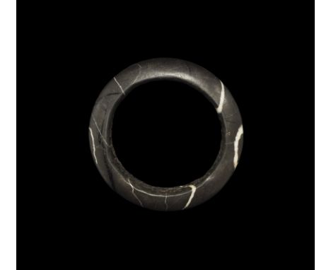 Neolithic Period, 5th-2nd millennium BC. A D-section bangle carved from grey slate with white and black banding. 119 grams, 1