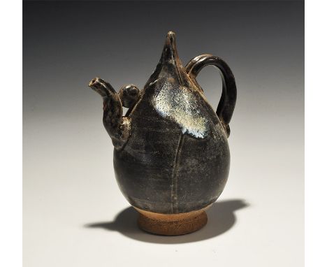 An undated archaistic ovoid glazed ceramic body with conical point, ribbed strap handle to the reverse, short S-curved applie
