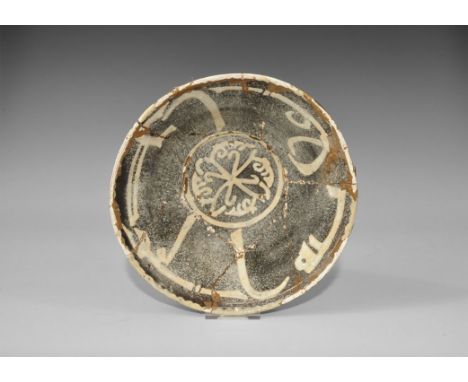 An undated archaistic black-glazed ceramic bowl with white calligraphic text to the inner wall, frond design to the centre. 5