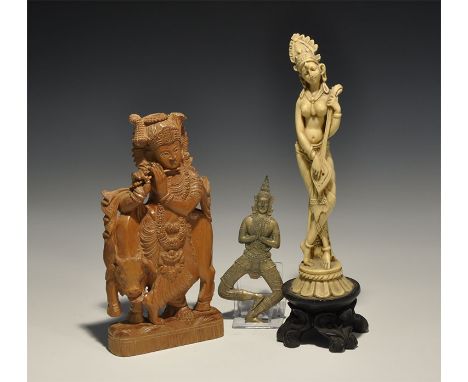 20th century AD. A mixed group of figural items comprising: an openwork wooden plaque of a robed figure of Krishna playing a 