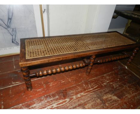 A late 19th / early 20th century, long stool, caned seating, raised on bobbin turned support, L: 92cm, H:23cm