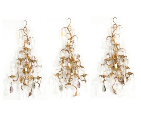 Three six-light wall lamps in embossed and gilded iron with crystal drops. 20th century. 80x35 cm approx. Tre applique sei lu