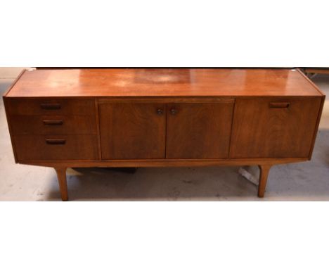 A c1960s teak sideboard, central twin doors opening to single shelf, flanked to left by three graduated drawers with integrat