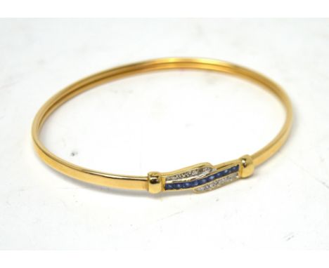 A 9ct yellow gold bangle set with central cornflower blue sapphires in a crossover diamond setting, approx 6.2g.