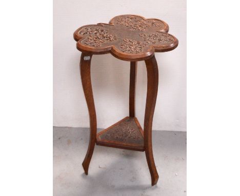 An oak shamrock-shaped occasional table with carved shamrock decoration, sweeping tripod legs leading to lower carved shelf, 