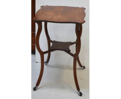 An Edwardian oak octagonal occasional side table with small lower shelf on curved tapering supports terminating in castors, d