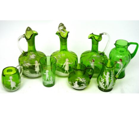 Three 19th century green glass decanters, four jugs and a beaker, all decorated in white enamel in the Mary Gregory style (8)