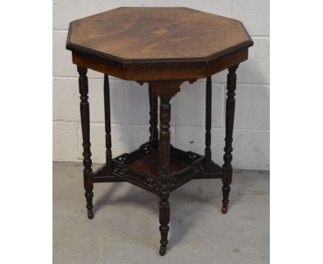 An Edwardian walnut veneer inlaid octagonal side table on turned supports with a lower gallery shelf, terminating in castors,