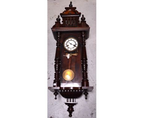An early 20th century German wall clock with turned supports to either side, white enamel dial set with Roman numerals, lengt