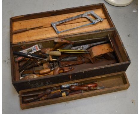 A vintage ebonised toolbox containing a quantity of tools to include chisels and saws.