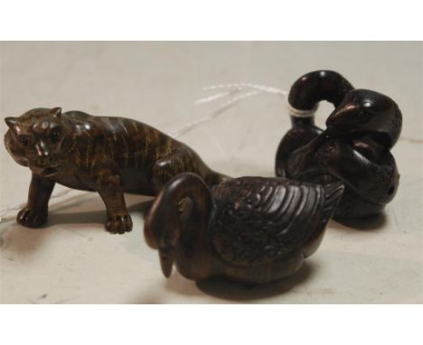 A carved wooden netsuke in the form of a tiger together with one other in the form of a bird and an entwined snake (3)