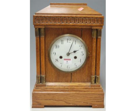 An early 20th century century oak cased mantel clock, of architectural form, having enamel dial with Arabic numerals and eigh