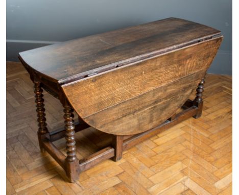 A basically 18th century oak gateleg dining table, the pegged rectangular top with demi-lune flaps over twin end drawers on b