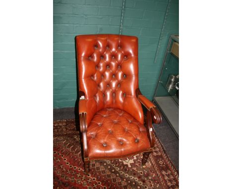 A 20th century red/brown button hide upholstered library armchair on ring turned forelegs and brass castors