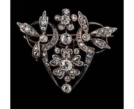 A Belle Epoque diamond brooch, pendant shield shaped, with central foliate diamond cluster within diamond set scrolling folia