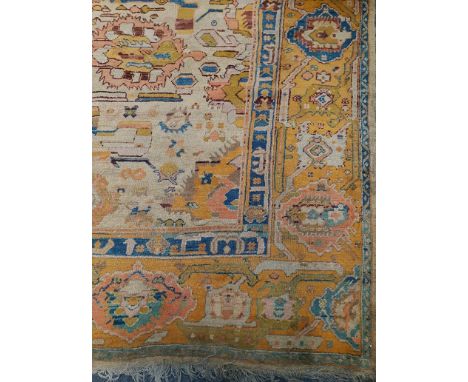 An early 20th century Turkish carpet, woven with stepped lozenge medallions on a busy floral field and primarily mustard grou