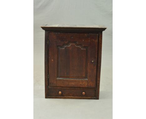 A MID 18TH CENTURY OAK SINGLE DOOR SPICE CUPBOARD, the moulded cornice above fielded panel door enclosing an arrangement of e