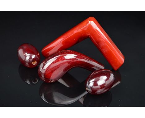 TWO RED PLASTIC WALKING STICK HANDLES AND TWO LARGE RED PLASTIC BEADS, one handle of curved shape, the other angled, lengths 