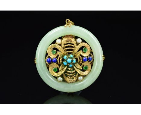 A 9CT GOLD JADE AND MULTI GEM PENDANT, of circular outline, the central 9ct gold panel of floral design with rope twist and t