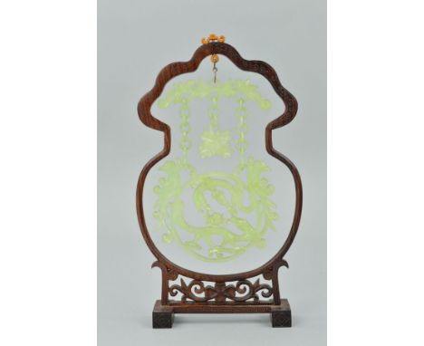 A 20TH CENTURY CARVED AND PIERCED JADE HANGING ORNAMENT, the scrolled bar with three chains suspended, the central one termin