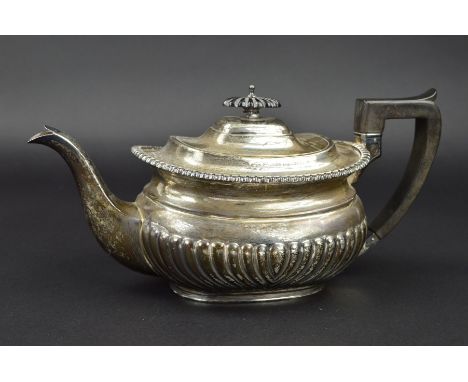 AN EDWARDIAN SILVER TEAPOT OF GEORGIAN STYLE, gadrooned rim, half reeded, ebonised fitments, makers Walter &amp; Charles Siss