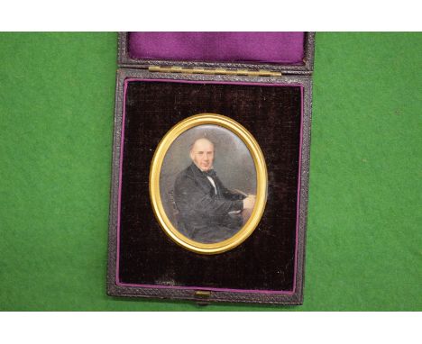 A portrait miniature of a Gentleman seated at a desk in a leather travelling case.