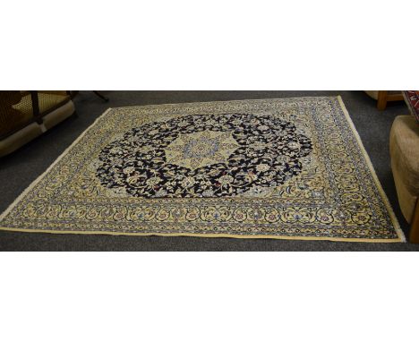 A Nain carpet, central Iran, deep indigo field of scrolling vines around a flowerhead pole medallion, framed by cream spandre