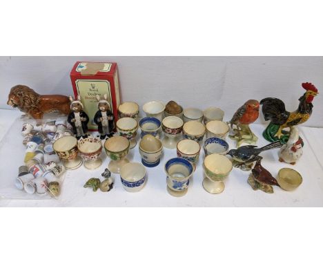 A collection of 19th century and later egg cups including Derby, together with thimbles and porcelain animals ornaments to in