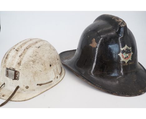 A vintage fireman's helmet together with a miner's hard hat