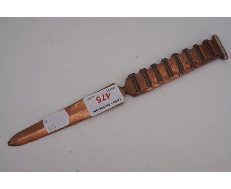 A Great War trench art paper knife fabricated from an artillery shell driving band and engraved "Monfalcone 1917"