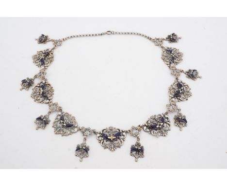 A late 19th / early 20th Century flamboyant enamelled electroplate necklace comprising a series of flowerhead-decorated blue 