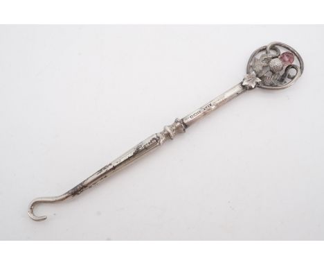 An Edwardian silver-handled button hook, the terminal modelled as a thistle and set with an amethyst-coloured stone