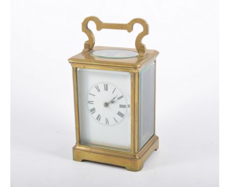 A French style timepiece carriage clock, the white enamel diam with roman numeral chapter ring in a plain brass case with ova