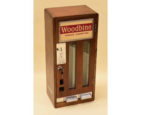 A VINTAGE CIGARETTE DISPENSER FOR WOODBINE in an oak case, 'INSERT 15p' with key (with staff for safe keeping), 67cms high