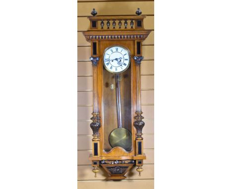 AN ANTIQUE VIENNA-STYLE WALL CLOCK with white enamel dial bearing Roman numerals, within a carved case, 112cms high