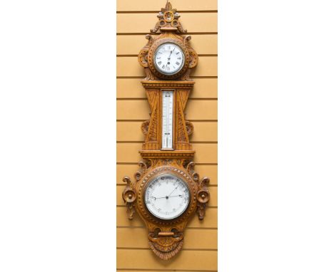 AN EARLY TWENTIETH CENTURY ANEROID BAROMETER the oak case heavily carved with floral and foliate decoration, surrounding a me