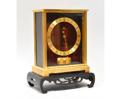 A JAEGER LECOULTRE ATMOS CLOCK with red marble effect face and side panels, brass chapter ring bearing Roman numerals, within